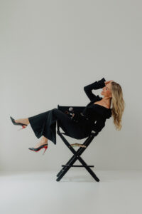 Hudson Valley personal branding photographer captures salon owner smiling in director’s chair during professional business photoshoot.