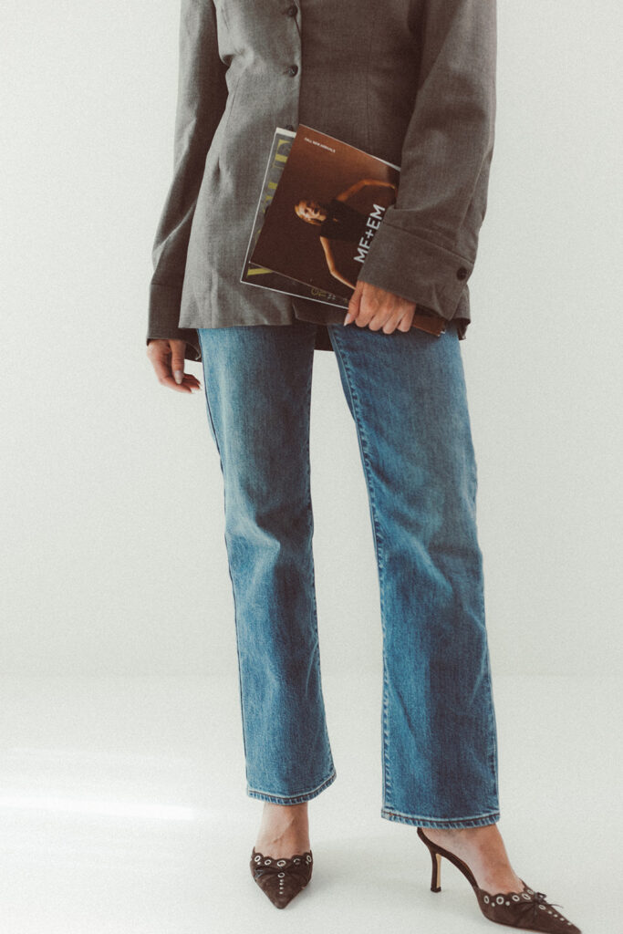 a model posing in fashionable clothes holding fashion magazines